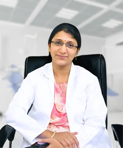 Dr. L. Divya seated in a white coat, hands folded, in a clinic chair