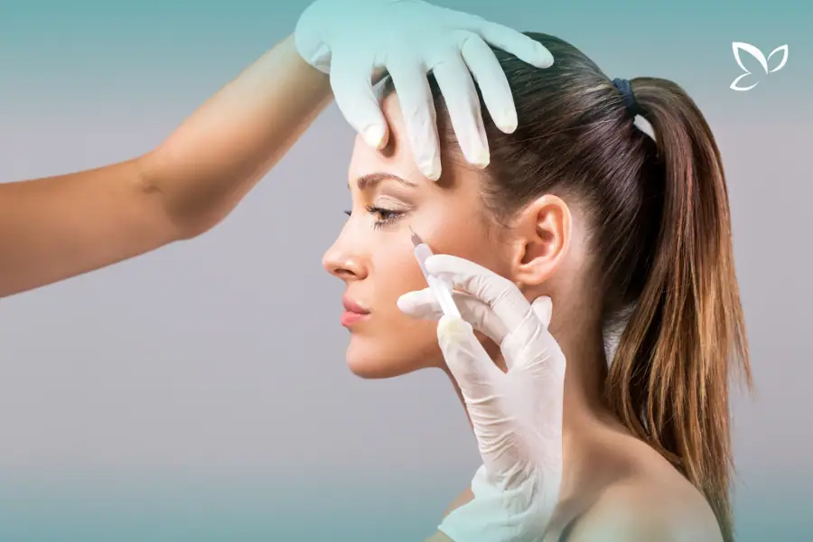 Gloved hands steadying the forehead during an injection near the eye